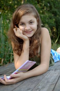 Teenage girl lying on a boardwalk with a book and a pen in her hand