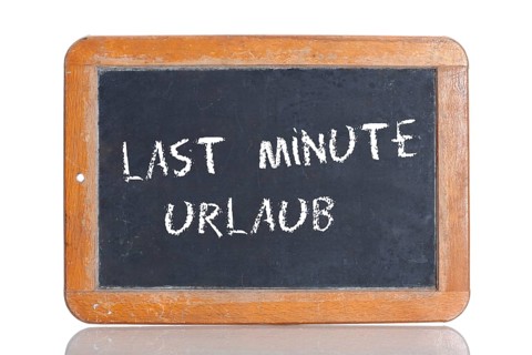 Old school blackboard with the words LAST MINUTE URLAUB