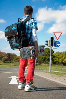 Boy with a school bag and a skateboard on a street
