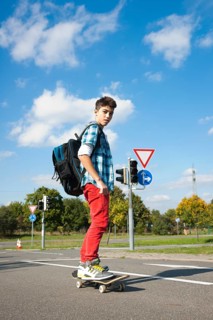 Boy with a school bag and a skateboard on a street