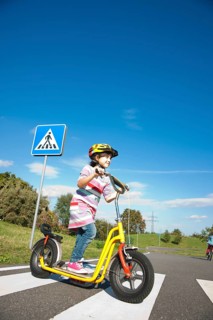 Girl crossing a zebra crossing with her scooter