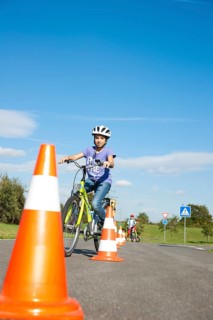 Children practicing to ride slalom on a bicycle at a traffic awareness course