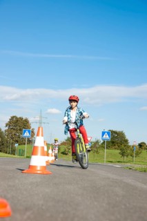 Child practicing to ride slalom on a bicycle at a traffic awareness course