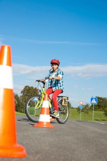 Child practicing to ride slalom on a bicycle at a traffic awareness course