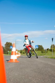 Child practicing to ride slalom on a bicycle at a traffic awareness course