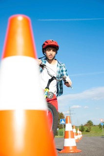 Child practicing to ride slalom on a bicycle at a traffic awareness course