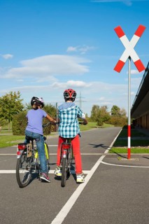 Children waiting with their bicycles in front of a railroad crossing at a traffic awareness course