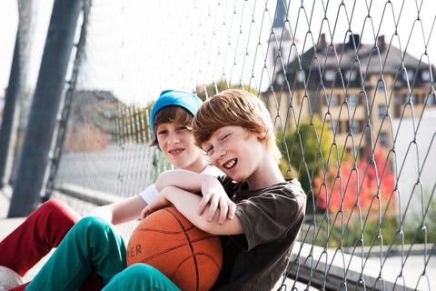 Two cool boys sitting with a basketball on a playground