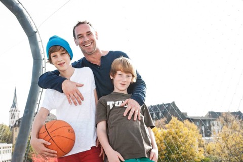 Two cool boys standing with their father on a playground