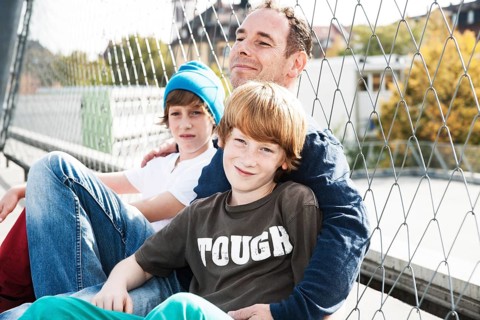Two cool boys sitting with their father on a playground