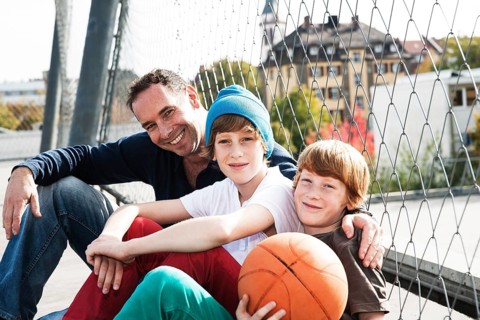 Two cool boys sitting with their father on a playground