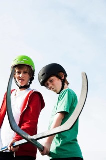 Two cool boys playing roller hockey with hockey sticks