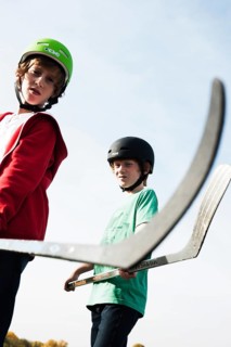 Two cool boys playing roller hockey with hockey sticks