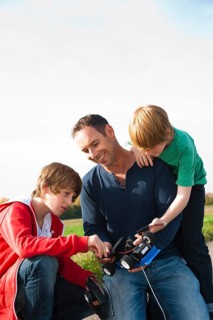 Father tinkering on a remote-controlled model car with his sons