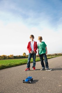 Two boys playing with a remote-controlled model car
