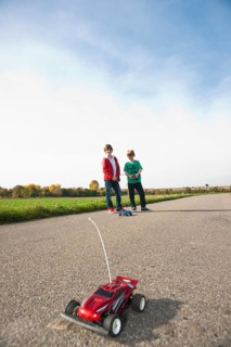 Two boys playing with a remote-controlled model car