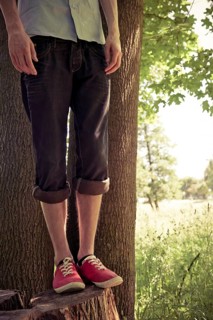 Lower section of young man standing on a tree stub