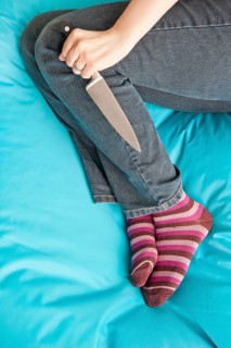Woman lying down and holding a knife in a firm grip