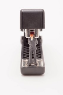 Figurine of businessman trapped by a stapler