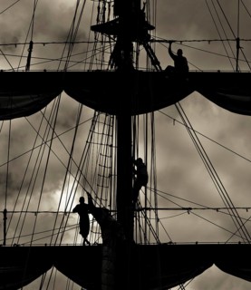Three sailors on the mast of a ship