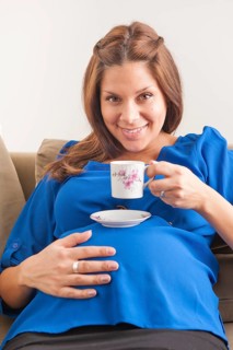 Smiling pregnant woman drinking coffee