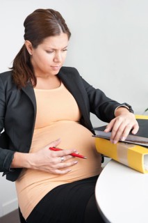 Pregnant woman sitting in an office looking troubled