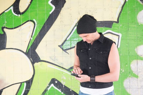 Man standing in front of wall covered with graffiti