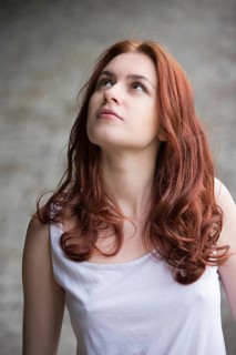 Pensive young woman with red hair looking up