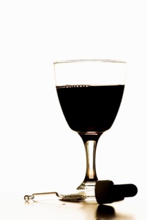Pipette lying in front of glass filled with red wine