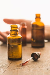 Medical bottles and pipette containing toxic fluid with hand of a victim of a crime in the back