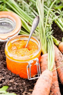 Raw carrots in a vegetable garden with carrot marmalade in a glass jar