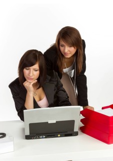 Two young women in an office looking at a laptop