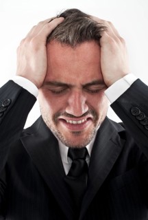 Desperate young man wearing a suit holding his hands to his face