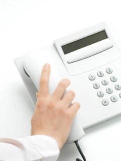 Woman hanging up the handset of a telphone