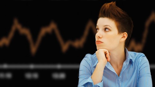 Business woman with a punk hairstyle in front of a stock exchange board