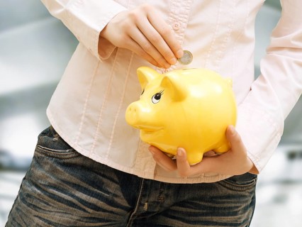 Girl putting euro coin into in piggy bank