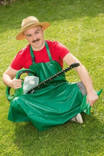 Gardener holding a hedge trimmer while sitting on the lawn
