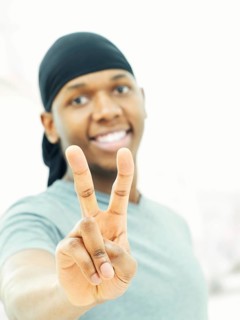 Dark-skinned man wearing a bandana and making a victory sign