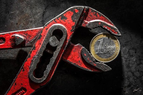 A Greek euro coin under pressure in a monkey wrench