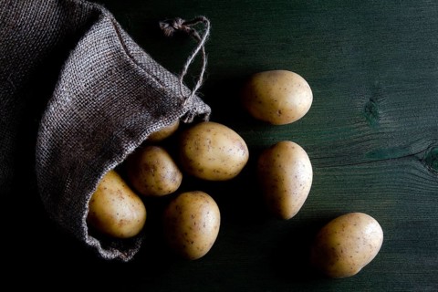 Potatoes in burlap sack on wood