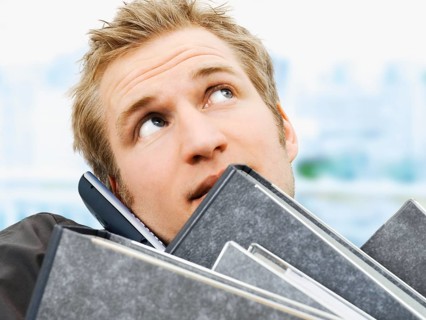 Businessman carrying ring binders while using a mobile phone