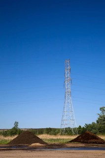 Mounds of topsoil and a hydro electricity transmission tower in a commercial sandpit