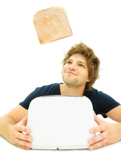 Young man looking at a slice of toast as it pops out of a toaster