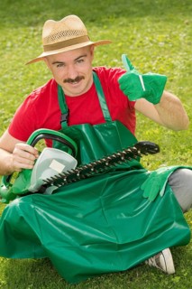 Gardener holding a hedge trimmer while sitting on the lawn
