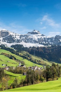 Green pastures in Appenzellerland with the community of Bruelisau and the snow-capped Appenzell Alps