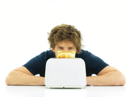 Young man behind a toaster with slices of toast