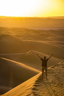 Man enjoying the sunset in the giant sanddunes of the Sahara