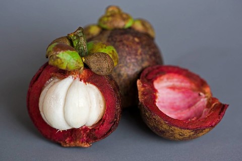 A halved and a whole Mangosteen (Garcinia mangostana)