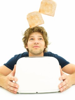 Young man looking at slices of toast as they pop out of a toaster