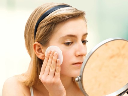 Young woman cleaning her face with a cotton pad